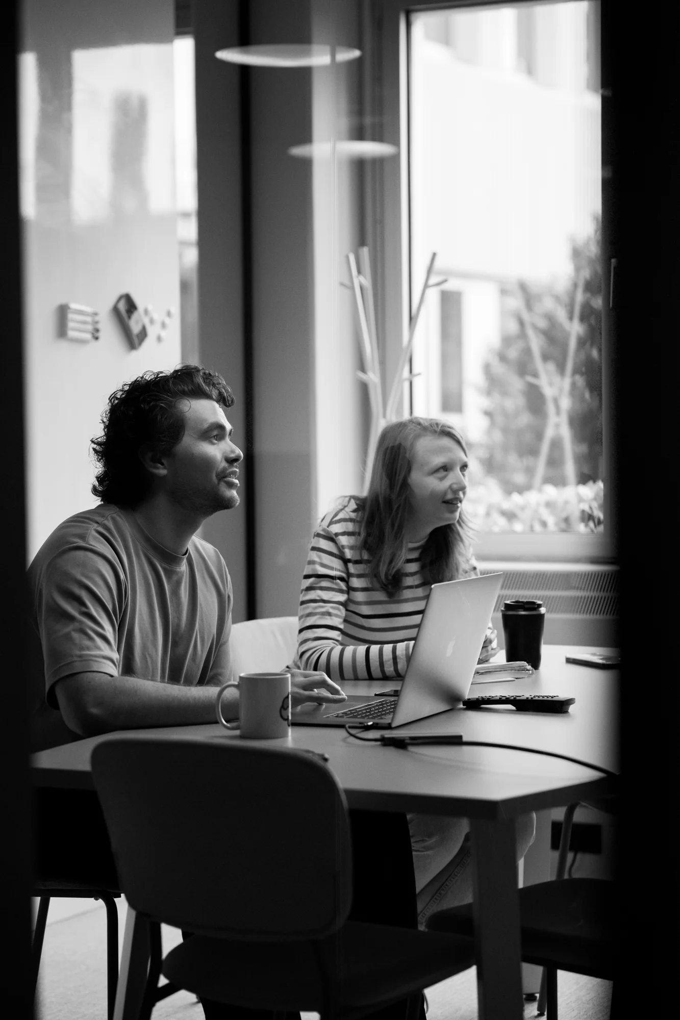 Duo aan tafel met laptop bij raam